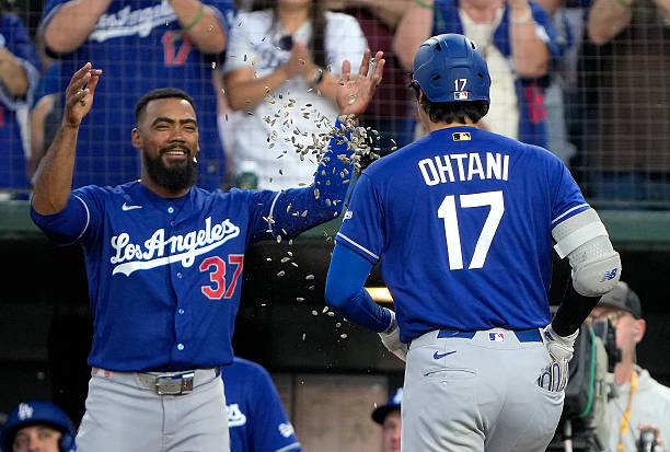 Shohei Ohtani of the Los Angeles Dodgers gets showered with sunflower seeds by Teoscar Hernandez after Ohtani hit a three-run home run against the...
