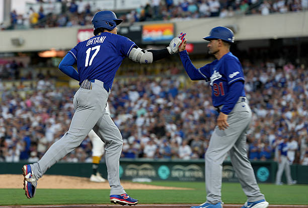 Shohei Ohtani of the Los Angeles Dodgers is congratulated by third base coach Dino Ebel after Ohtani hit a three-run home run against the Athletics...