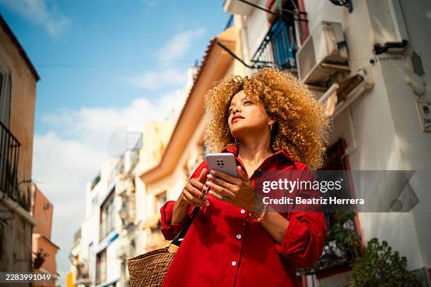 mujer hondureña viajando sola explorando calles de la ciudad con smartphone - registro fotografías e imágenes de stock