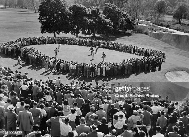 Spectators look on as Sam Snead from the United States makes a putt on the 18th Green to card a 17 under par 263 to win the Greenbrier Pro-Am golf...