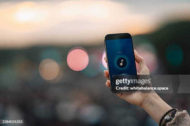 woman using smartphone to identify song at music festival - streaming service stock pictures, royalty-free photos & images