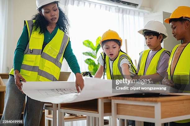 teacher explaining engineering blueprint to students during stem learning activity - child architect stock pictures, royalty-free photos & images