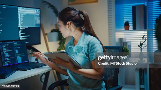 gen z asian female computer programmer uses digital tablet for coding while working late in home office. software development, technology innovation, artificial intelligence, working at home concept. - data science stock pictures, royalty-free photos & images