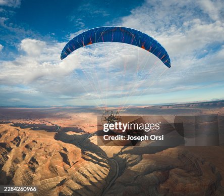 Paramotor soaring over winding desert river canyon Paramotor soaring over winding desert river canyon