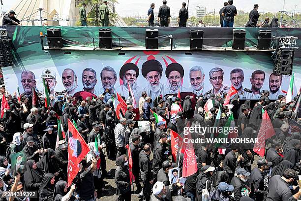 Mourners gather around one of the vehicles in the funeral procession for Iran's slain Supreme Leader Ali Khamenei at Azadi Square in Tehran on July 6...
