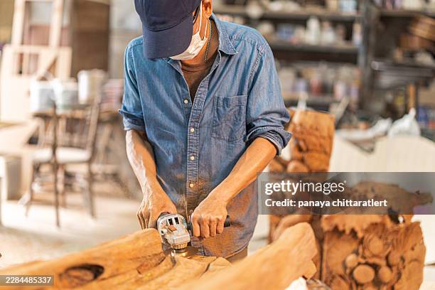 asian craftsman using angle grinder to shape wood sculpture in workshop - mask angles stock pictures, royalty-free photos & images