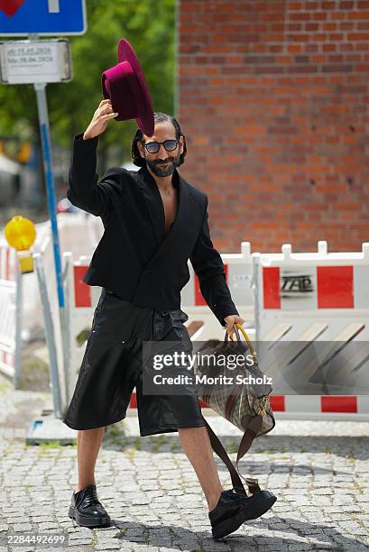 Massimo Sinató is seen wearing a black cropped blazer; black leather knee length shorts; black leather lace up shoes; a medium sized beige monogram...