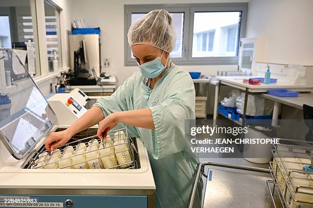 Technician places racks of milk bottles into the pasteuriser in the pasteurisation room of the breast milk bank at the maternity ward of the Nancy...