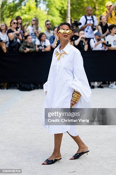 Guest wears white button dress, golden necklace, bracelet, sunglasses outside Schiaparelli during Day One of Paris Fashion Week - Haute Couture...