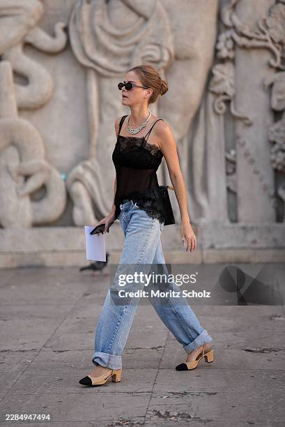 Guest is seen wearing a sheer black lace camisole with delicate lace trim, light wash cuffed wide leg jeans, beige and black cap toe slingback pumps,...