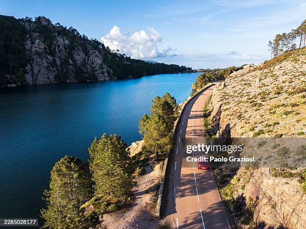 car driving along a mountain lake at sunset - mountain road stock pictures, royalty-free photos & images
