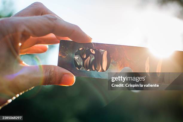 hand holding eclipse glasses for sun protection and viewing - eclipse solar imagens e fotografias de stock