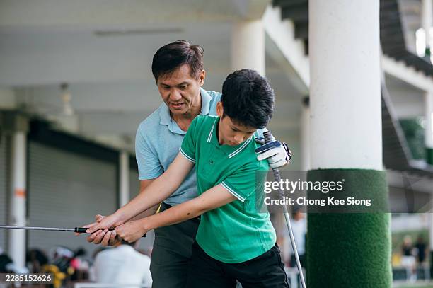 golf coach correcting young player's swing posture during lesson - golfer stock pictures, royalty-free photos & images