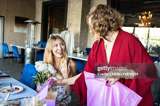 blonde woman smiling as she receives personalized gift box and flowers from friend - long receipt stock pictures, royalty-free photos & images