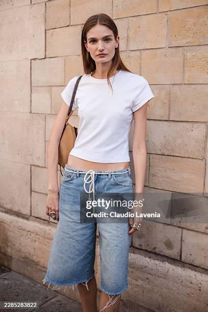 Guest wears a white cropped short-sleeve cotton T-shirt, light blue denim bermuda shorts with a white rope drawstring belt and raw-hem cuffs, and...