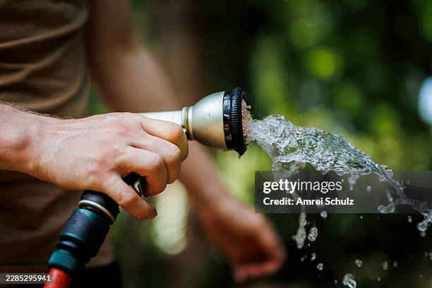 Man watering plants with a garden hose in a garden on July 13, 2026 in Berlin, Germany.
