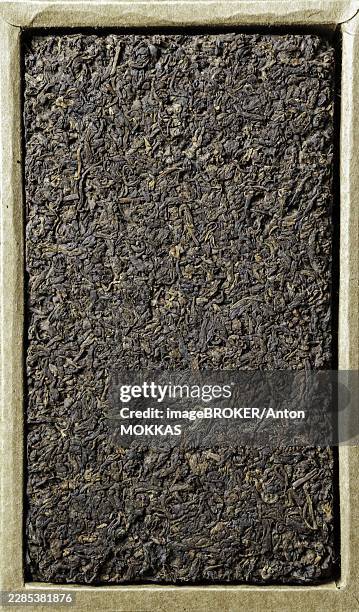 a closeup view of a dense black tea leaf cake, beautifully highlighting its rich texture and earthy tones - tea leaf pattern stock pictures, royalty-free photos & images