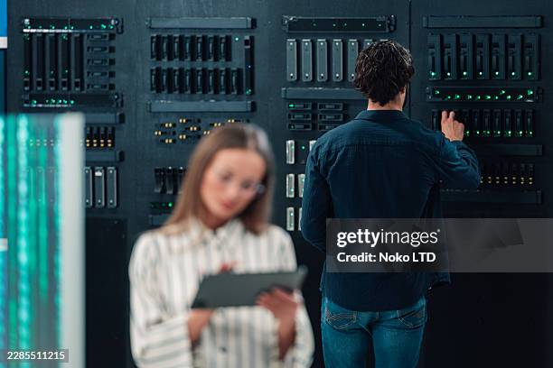 it specialists working in a data server room, managing cloud computing infrastructure and secure network storage - installing software stock pictures, royalty-free photos & images