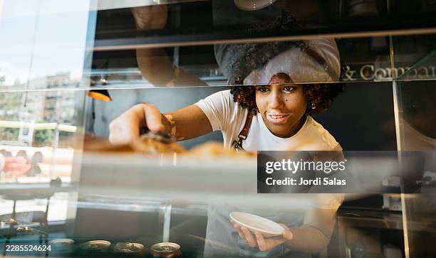 server placing pastry in bakery display case - depigmentation stock pictures, royalty-free photos & images