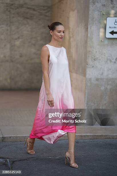 Guest is seen wearing a white to bright pink ombré satin maxi dress with wide draped sleeves; nude transparent high heel sandals; small stud earrings...