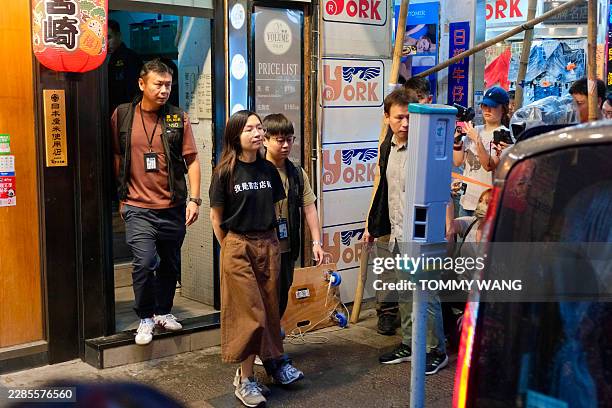 An independent bookstore employee is being led away by policemen after the officers raided the "Have A Nice Stay" bookshop and confiscated items in...
