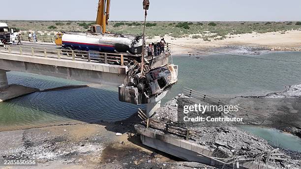 In this handout photo by Morteza Akhoundi via Getty Images, workers clean up wreckage around a damaged bridge, following U.S. Airstrikes carried out...