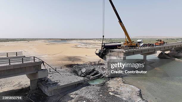 In this handout photo by Morteza Akhoundi via Getty Images, workers clean up wreckage around a damaged bridge, following U.S. Airstrikes carried out...