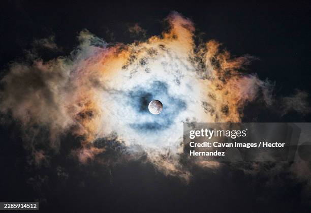 stunning partial lunar eclipse glowing behind colorful clouds - moon eclipse stock pictures, royalty-free photos & images
