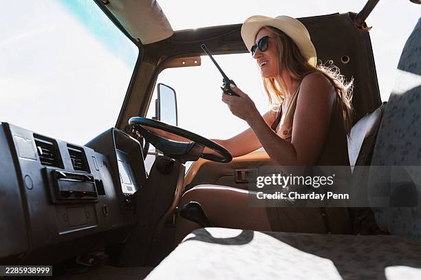 female game ranger with walkie talkie in ranger truck wearing hat and sunglasses on summer safari trip - portable radio stock pictures, royalty-free photos & images