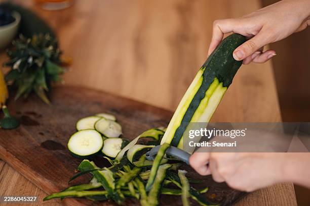femme épluchant des courgettes pour une préparation saine - éplucher photos et images de collection