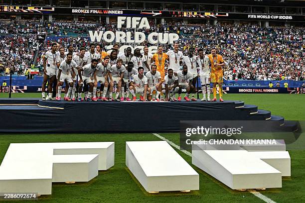 England's players pose for a photo with their medals after winning the 2026 World Cup football tournament third-place match between France and...