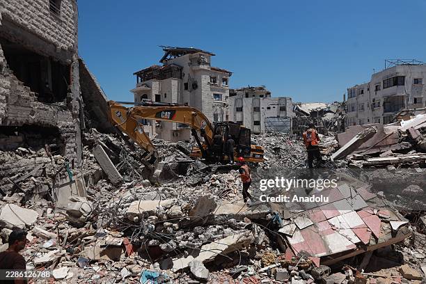 Civil defense teams work to recover the bodies of Palestinians, trapped under the rubble of a building destroyed in an Israeli military attack, with...