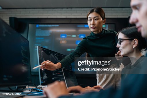 Senior women software developer advising the program structure and work flow to coder team on in meeting room. Senior women software developer advising the program structure and work flow to coder team on in meeting room.