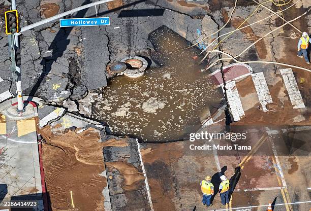 In an aerial view, utility repair workers gather near a sinkhole on Sunset Boulevard where a water main break flooded surrounding streets on July 16,...