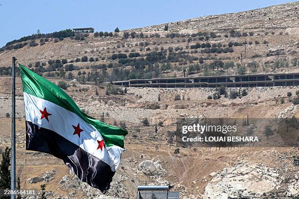 The Syrian flag flies at the Umayyad Square in Damascus on July 22 with Mount Qasioun pictured in the background. Syria's new leaders, who inherited...