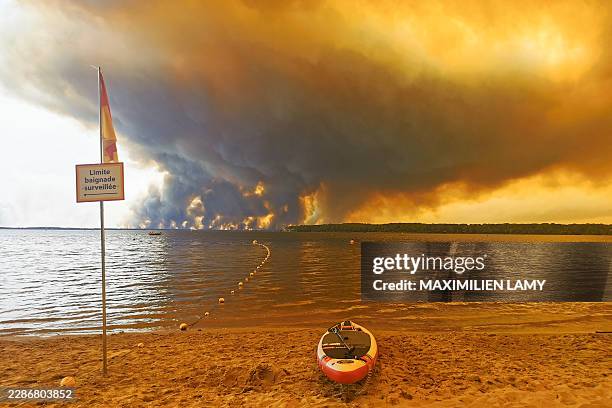 An information board marking the limit of the supervised swimming area stands on Moutchic Beach in Lacanau, southwestern France, July 24 as smoke...