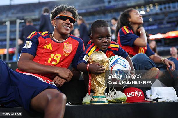 Lamine Yamal of Spain celebrates with his little brother Keyne and the FIFA World Cup Winner's Trophy after the team's victory following the FIFA...