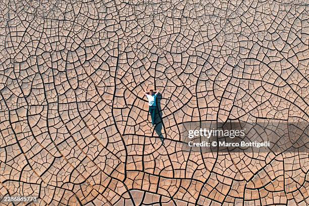 man lying on cracked dry earth seen from directly above, kyzylkup, mangystau - salt flat stock pictures, royalty-free photos & images