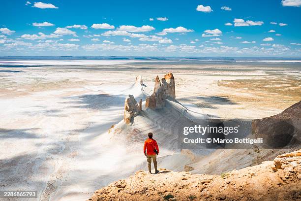 hiker overlooking chalk pinnacles and the salt plain, bozzhyra, mangystau - salt flat stock pictures, royalty-free photos & images