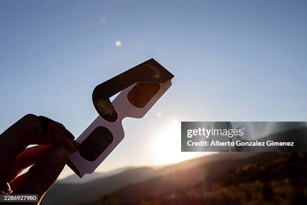 person holding solar eclipse glasses watching sunset in spain - eclipse foto e immagini stock