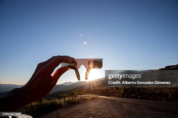 person holding eclipse glasses viewing solar eclipse in spain - solar eclipse stock-fotos und bilder