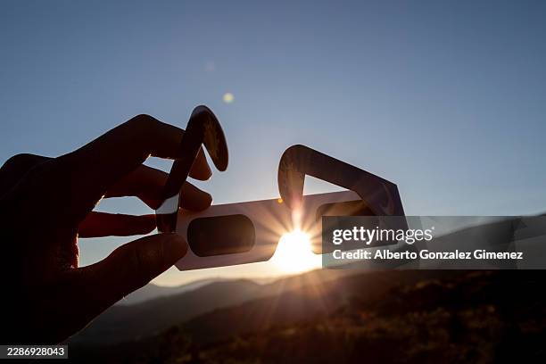 hand holding eclipse glasses observing solar event in spain - eclipse foto e immagini stock