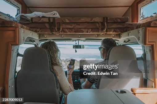 Erwachsenes weißes Paar blickt aus einem geparkten Wohnmobil auf den Ozean Erwachsenes weißes Paar blickt aus einem geparkten Wohnmobil auf den Ozean