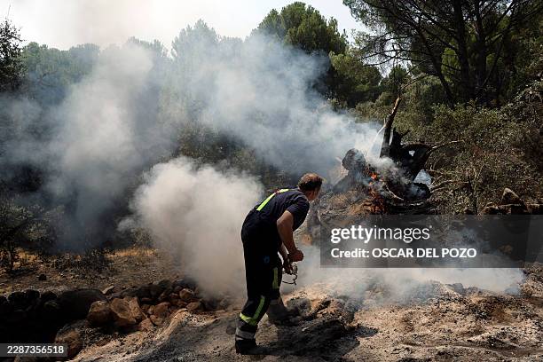 Man smothers embers with dirt to prevent reignition after a wildfire was brought under control near La Adrada, 95 kilometres west of Madrid, on July...