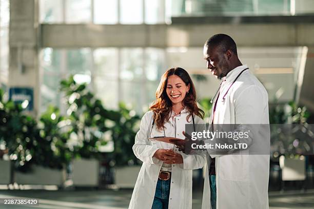 two healthcare professionals discussing in a modern hospital setting - business talk stock pictures, royalty-free photos & images