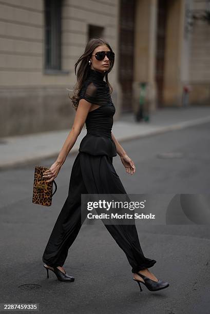 Lisa Mottl is seen wearing a black two piece set from Twen2's featuring a fitted sleeveless top with a sheer high neck overlay and sculptural peplum...