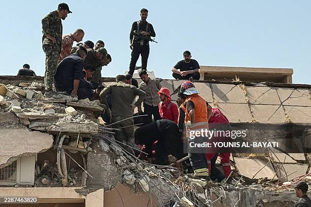 Security forces and emergency personnel work at the site of US-Saudi strikes that targeted a base belonging to Iraq's Hashed al-Shaabi Forces north...