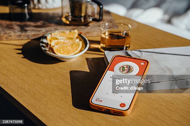 close-up shot of a smartphone with food ordering mobile app from device screen on a table next to some fresh fruits and tea at home. food delivery mobile app. people, food, lifestyle and technology - contactless delivery stock pictures, royalty-free photos & images
