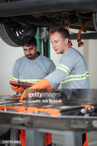 Auto mechanic explaining the problem to the customer while using digital tablet in a repair shop Auto mechanic explaining the problem to the customer while using digital tablet in a repair shop