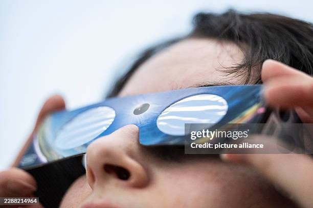 August 2026, Baden-Württemberg, Stuttgart: An employee at a specialty photography store is wearing solar eclipse glasses . Photo: Marijan Murat/dpa